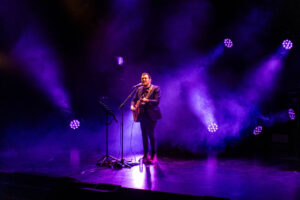 Isma Serrano actuando en un escenario con luces moradas