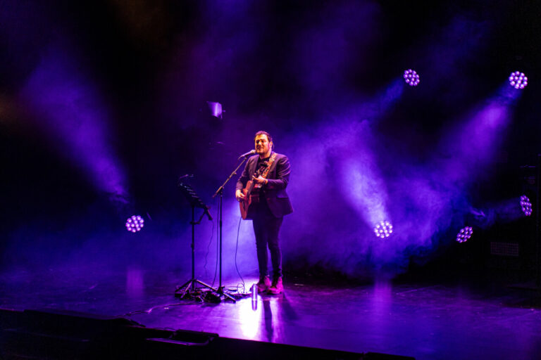 Isma Serrano actuando en un escenario con luces moradas