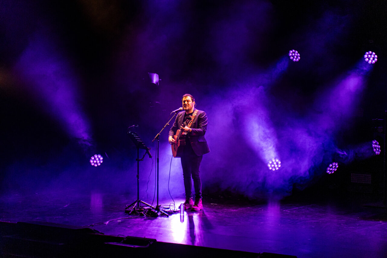 Isma Serrano actuando en un escenario con luces moradas