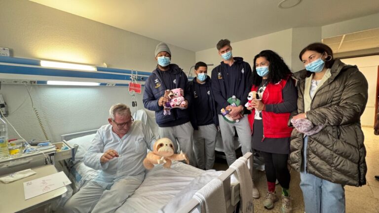 Jugadores entregando peluches a un paciente en el hospital