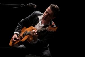 Santiago Auserón tocando la guitarra en un concierto acústico