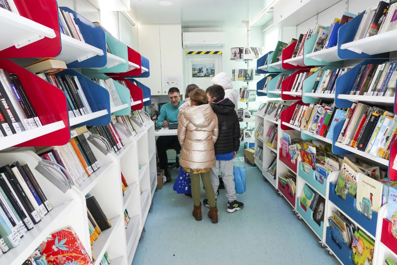 Niños en el interior de un bibliobús interactuando con el bibliotecario.
