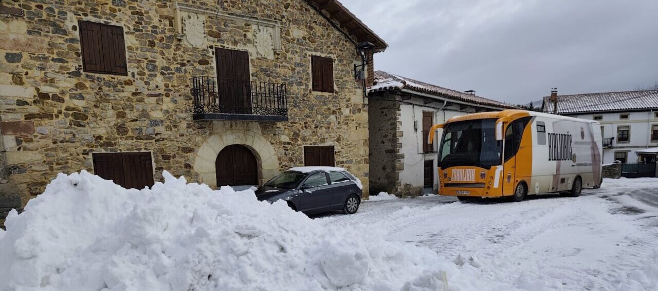 Bibliobús estacionado en un pueblo cubierto de nieve
