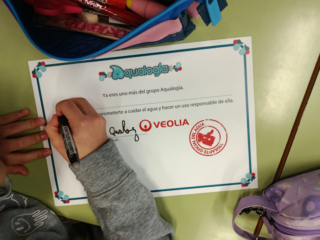 Niño escribiendo en un certificado del programa Aqualogía de Veolia