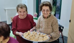 Dos mujeres mayores sosteniendo una bandeja con croquetas recién hechas
