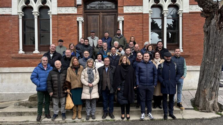 Grupo de personas posando frente a un edificio de ladrillo