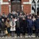 Grupo de personas posando frente a un edificio de ladrillo