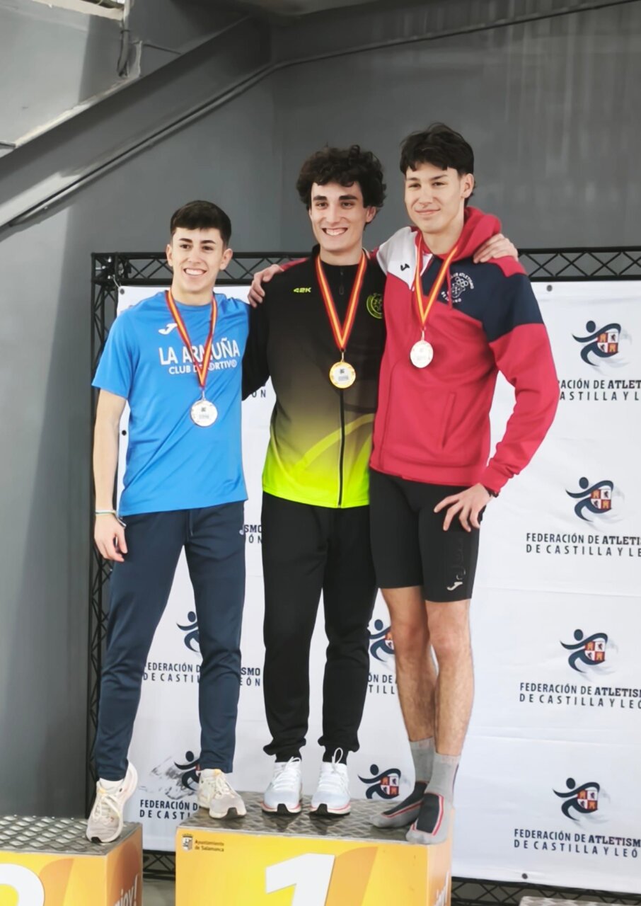 Tres atletas en el podio con medallas tras una competición de atletismo