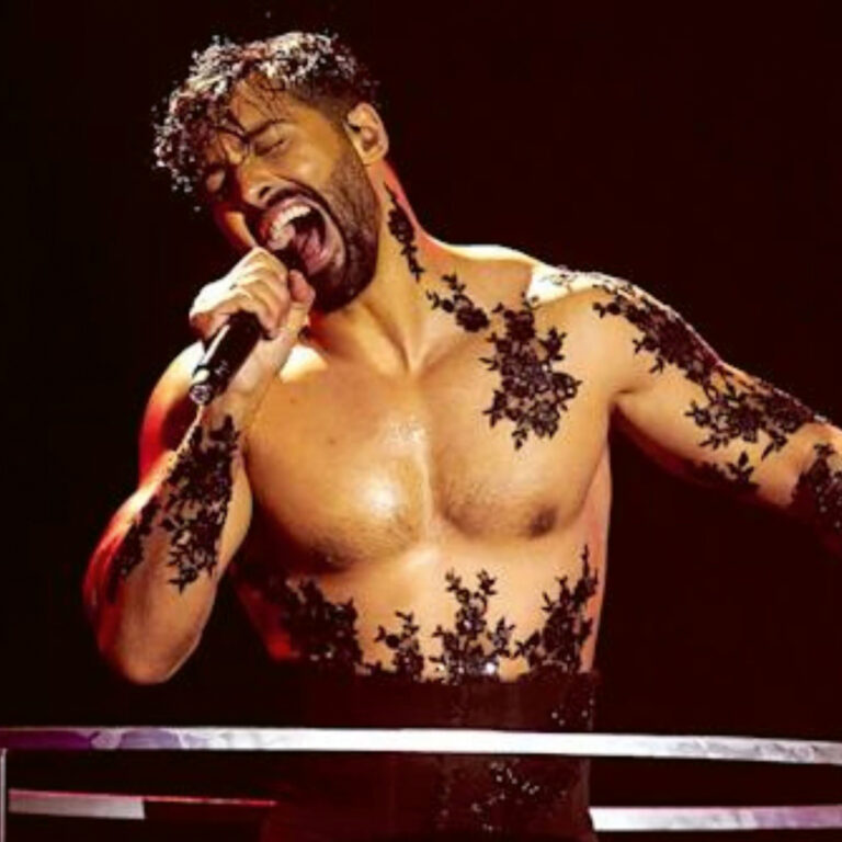 Jorge González cantando en un escenario con atuendo artístico