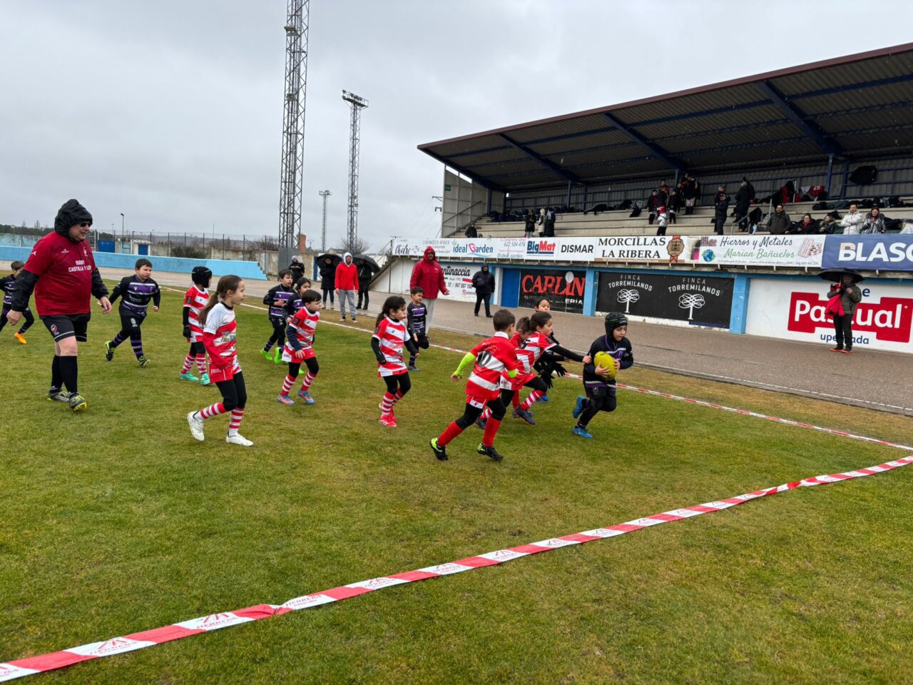 Niños jugando rugby en un campo durante un festival deportivo en Aranda.