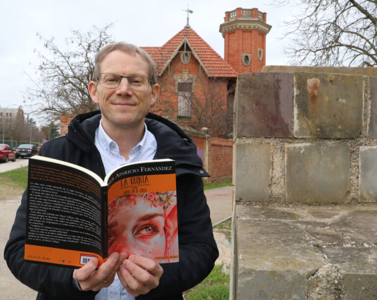 Asier Aparicio sosteniendo su libro La Quinta frente a un edificio antiguo
