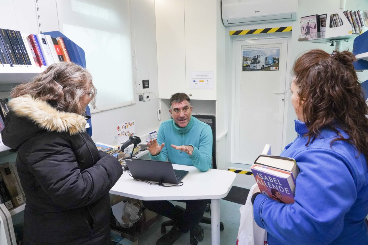 Bibliotecario interactuando con dos mujeres en un bibliobús.