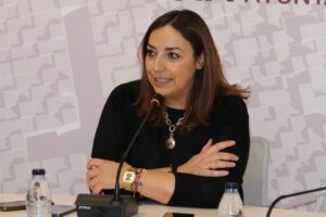 Mujer hablando en una conferencia con micrófono y manos cruzadas