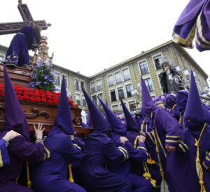 Nazarenos en Palencia cargando un paso durante una procesión