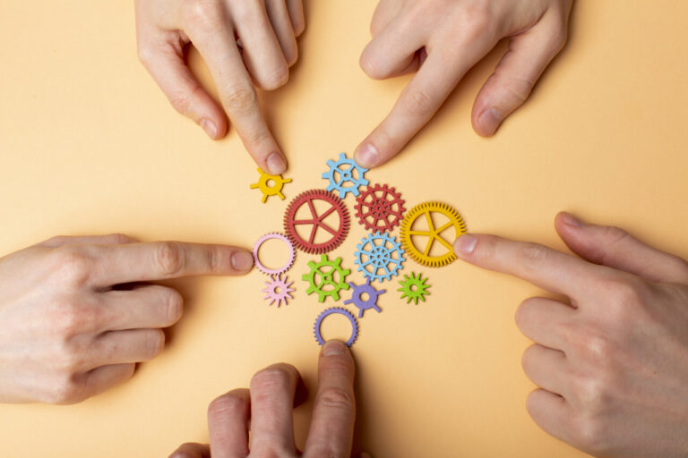 Manos señalando engranajes de colores sobre fondo claro