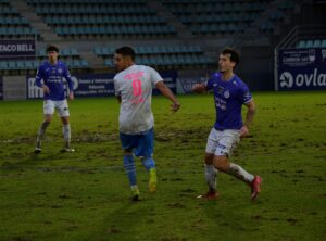 Jugadores de fútbol en un campo con césped en mal estado