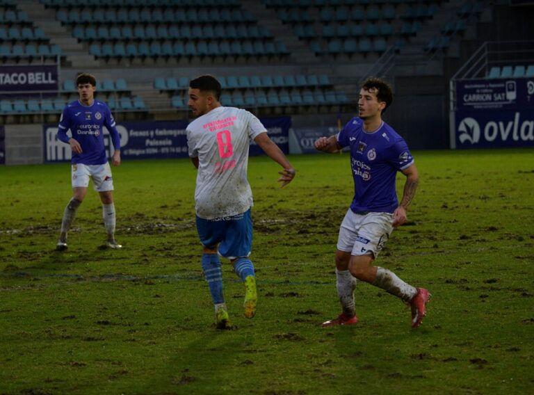 Jugadores de fútbol en un campo con césped en mal estado