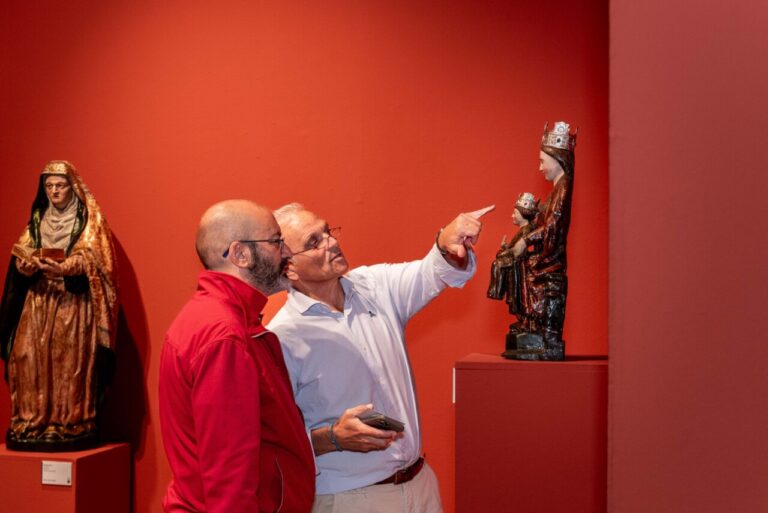 Dos hombres observan una escultura en un taller de restauración de arte.