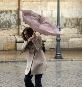 Mujer luchando contra el viento con un paraguas en Palencia