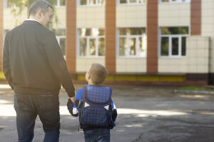 Padre y niño caminando hacia la escuela en su primer día escolar