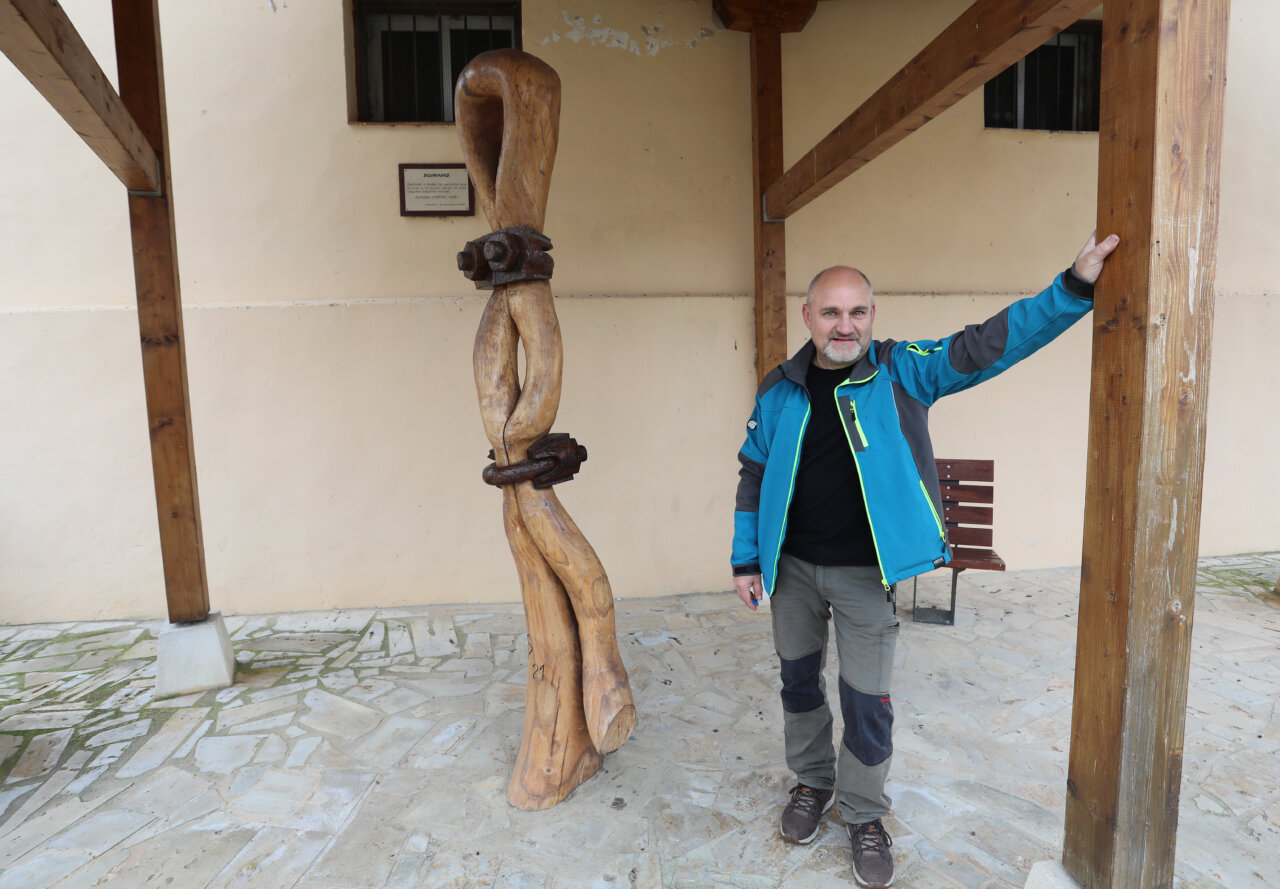 Alfredo Martín 'Chis' junto a su escultura de madera en Ampudia