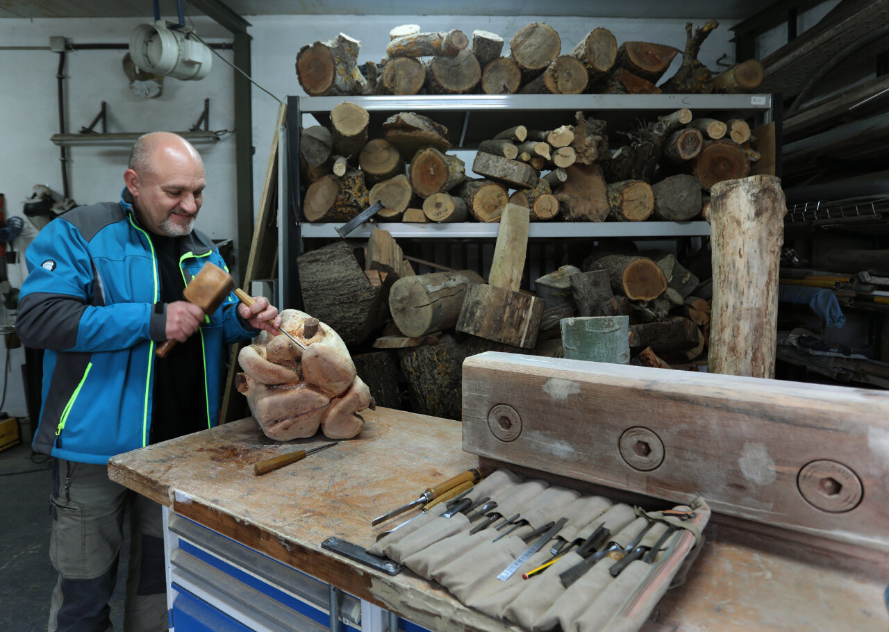Escultor trabajando la madera en su taller con herramientas