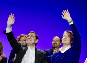 Acto político con personas saludando en un escenario