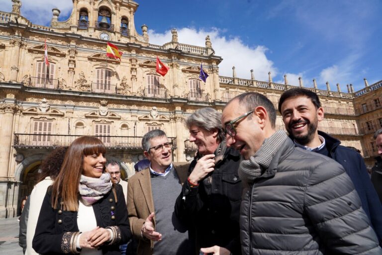 Candidatos del PSOE conversando en la plaza con edificio histórico al fondo