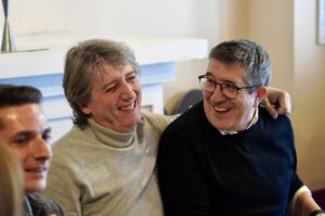 Dos hombres sonriendo en un ambiente amigable durante un evento político.