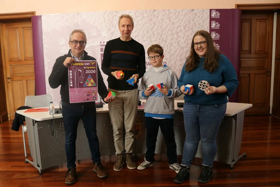 Cuatro personas sosteniendo cubos de Rubik y un cartel del campeonato en Palencia