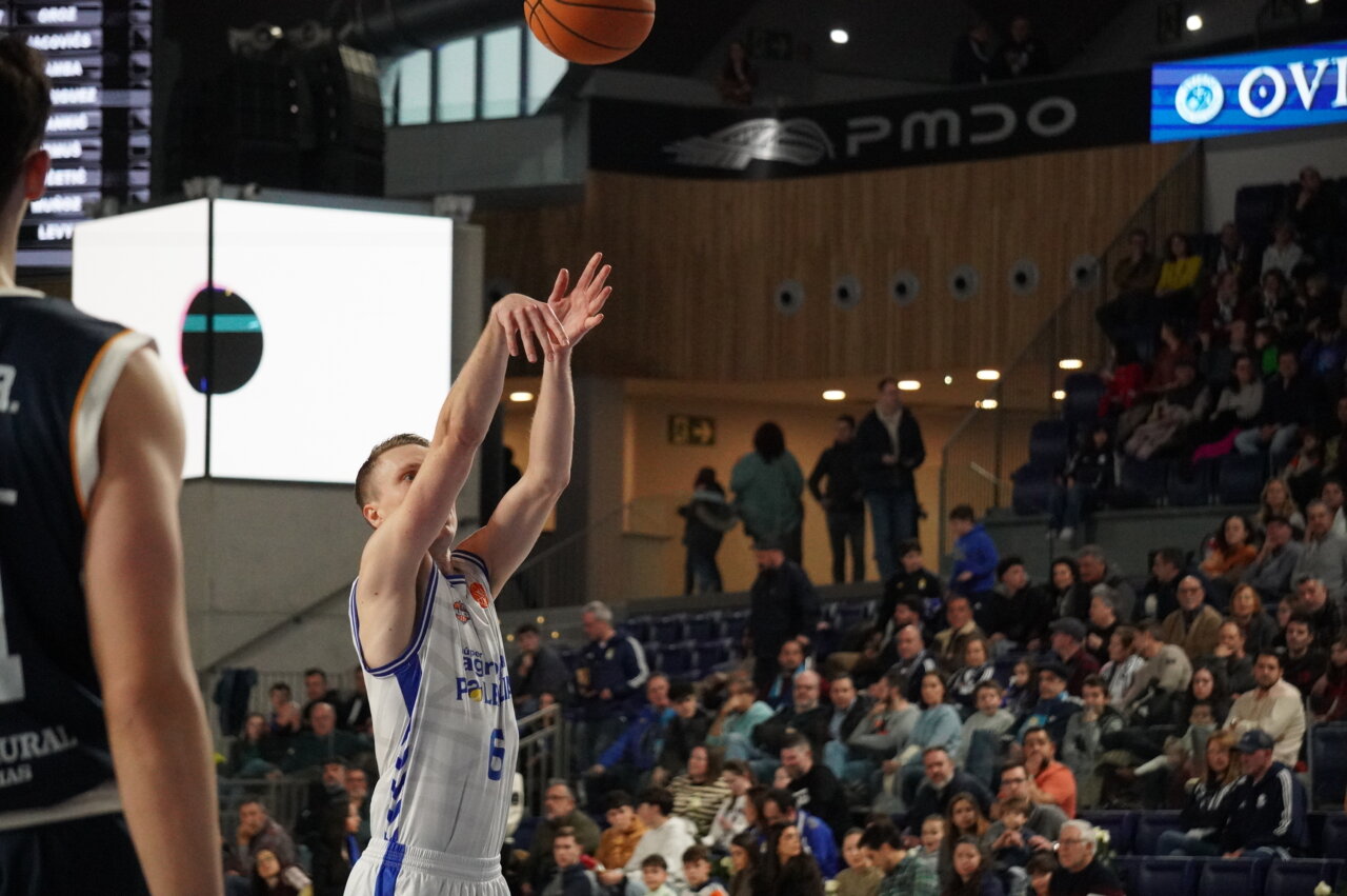 Jugador lanzando a canasta en un partido de baloncesto