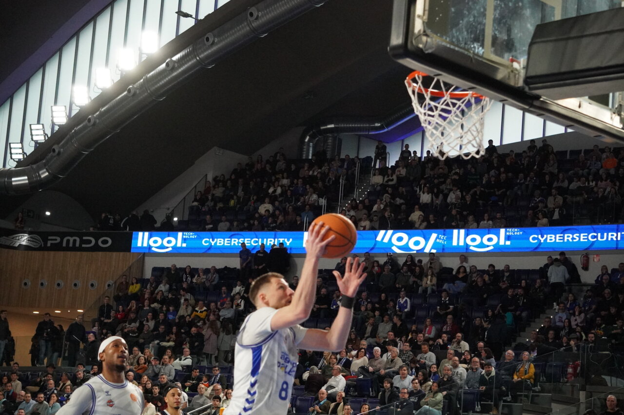 Jugador lanzando a canasta en un partido de baloncesto
