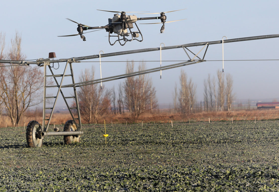 Dron agrícola sobre un campo inundado aplicando tratamientos a cultivos