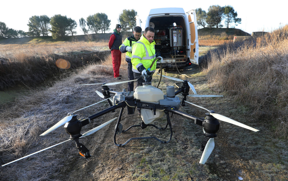 Dron agrícola en un campo con trabajadores preparando su uso