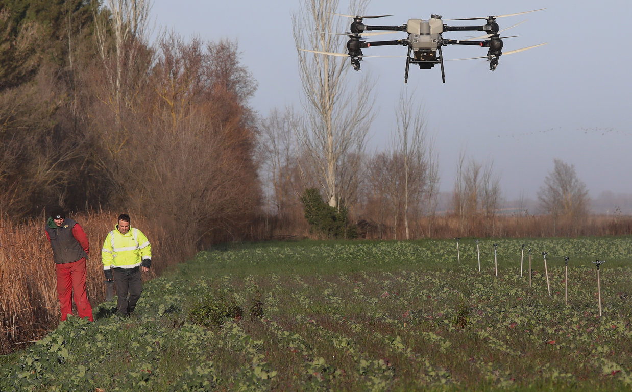 Dron volando sobre un campo con agricultores observando