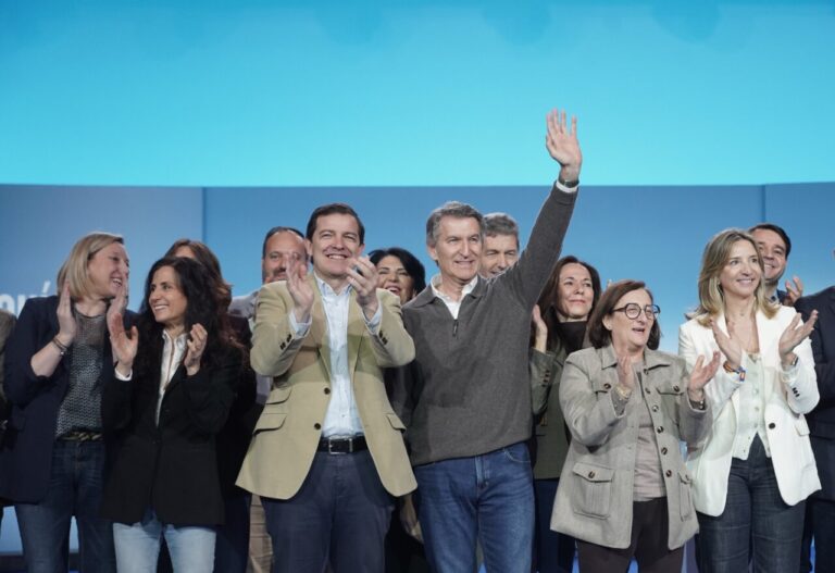Candidatos del PP en un evento político aplaudiendo y sonriendo.