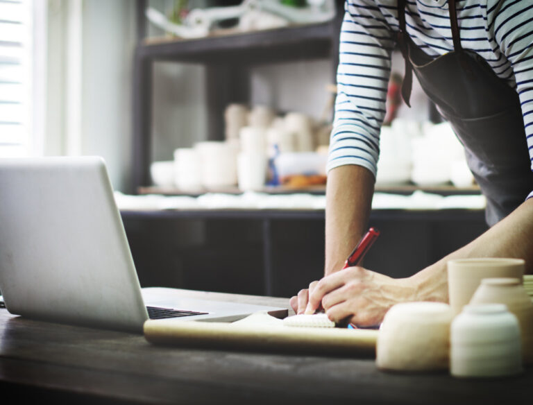 Artesano trabajando en un portátil en su taller de cerámica