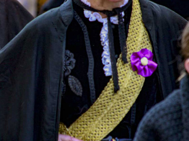 Mujer con banda dorada y atuendo tradicional en evento cultural