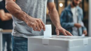 Un ciudadano depositando su voto en una urna electoral en una mesa de votación.