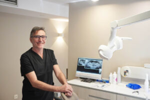 Dentista sonriente en su clínica dental con equipo moderno
