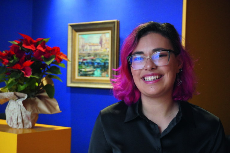 Cristina Saavedra, joven escritora con cabello rosa y gafas sonriente