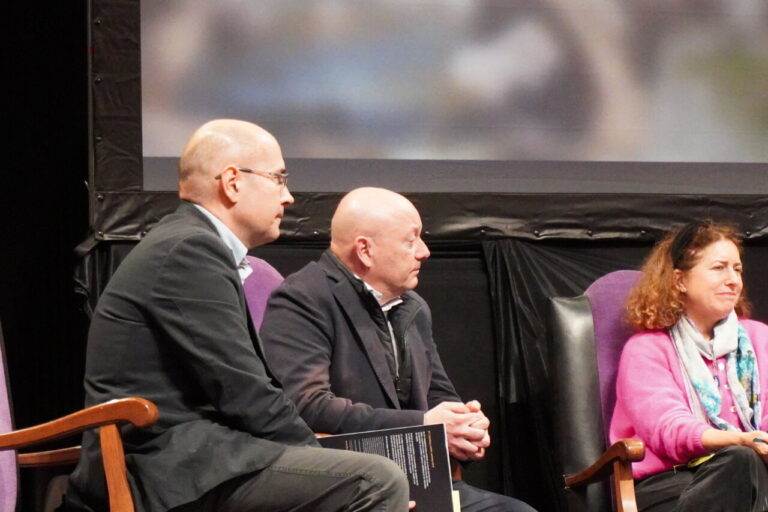 Tres personas sentadas en un panel de discusión durante un evento