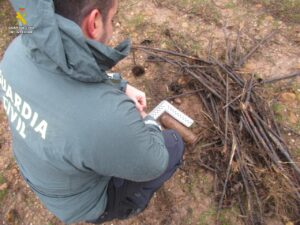Miembro de la Guardia Civil inspeccionando un proyectil de la Guerra Civil