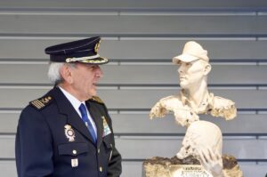 Un oficial de policía junto a una escultura de un compañero