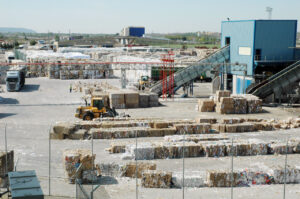 Vista de la planta de reciclaje de papel en Dueñas con maquinaria y balas de papel.
