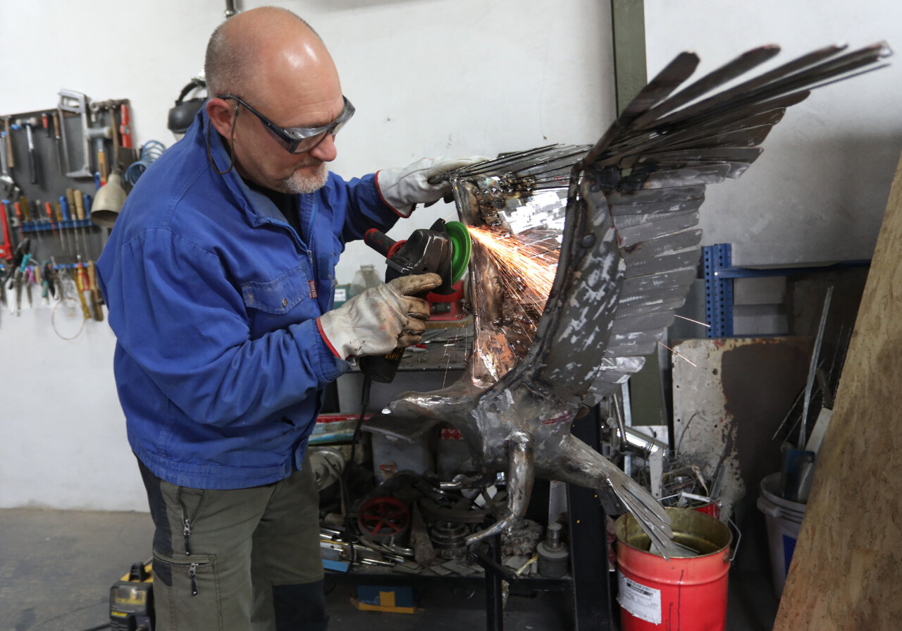 Escultor trabajando en una escultura de metal en su taller