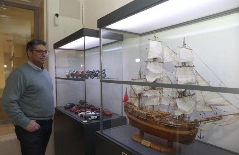 Hombre observando maquetas de barcos y vehículos en una vitrina