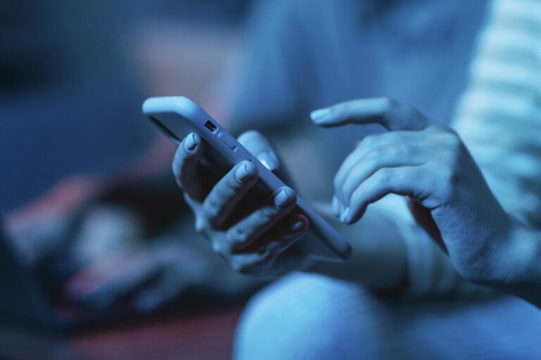 Mujer usando su smartphone en un ambiente oscuro y moderno.