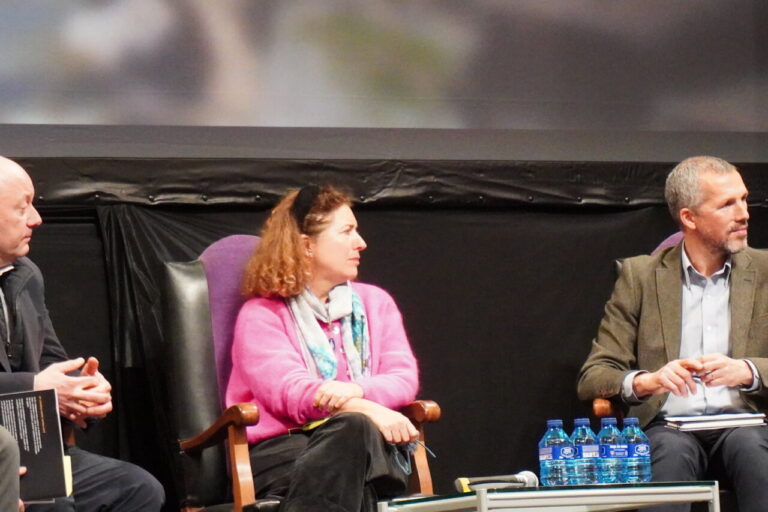 Panel de discusión con tres personas en un escenario