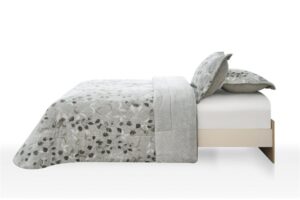 Cama con edredón y cojines decorativos en tonos grises